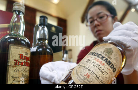 Die Scotch Whisky Experience Mitarbeiterin Grace Fan reinigt eine Flasche aus der weltweit größten Whisky-Sammlung, die heute in ihrem neuen Zuhause in Edinburgh angekommen ist. Stockfoto