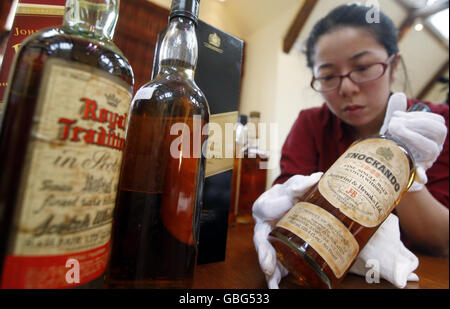 Die Scotch Whisky Experience Mitarbeiterin Grace Fan reinigt eine Flasche aus der weltweit größten Whisky-Sammlung, die heute in ihrem neuen Zuhause in Edinburgh angekommen ist. Stockfoto