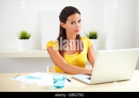 Erwachsenes Weibchen in gelber Kleidung arbeitet als Empfangsdame in einem Unternehmen Stockfoto