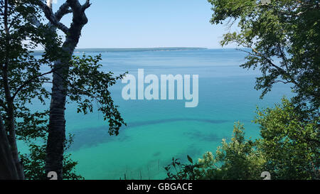 Seeblick des blauen Wassers durch die Bäume. Munising Wanderweg Aussichtspunkt des Lake Superior. Stockfoto
