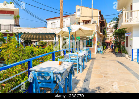 Insel SAMOS, Griechenland - SEP 19, 2015: Tische mit Stühlen auf traditionelle griechische Taverne auf Straße der Stadt Kokkari, Griechenland. Stockfoto