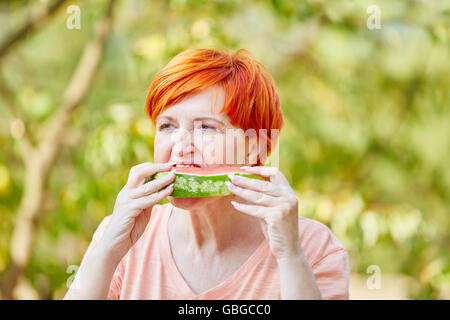 Ältere Frau essen eine gesunde Wassermelone im Sommer Stockfoto