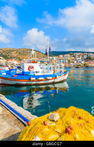 Fischernetz im Vordergrund mit traditionellen Fischerboot in Ferne in Pythagorion Hafen auf der Insel Samos, Griechenland Stockfoto