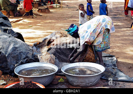 eine alte Frau, die kochen lokale Bier aus Hirse in Burkina Faso genannt Dolo mitten auf einer Straße in Bobo-Dioulasso Stockfoto