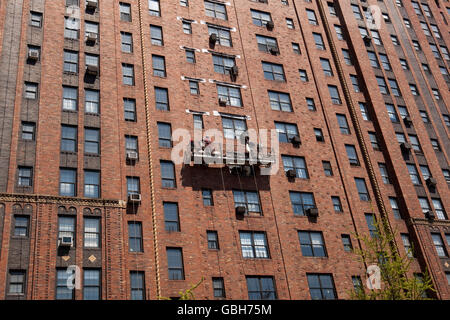 Männer auf einem Fensterreinigungs-Plattform hängen von der Seite der London Terrassengärten Gebäude in New York, USA, 24. April 2009 Stockfoto