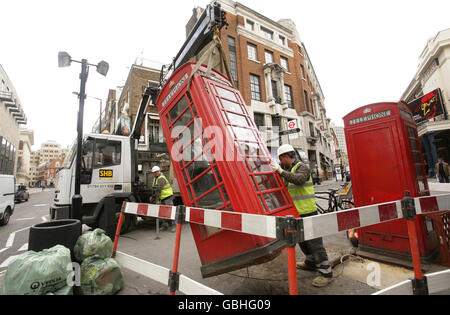 Arbeiter entfernen eine rote öffentliche Telefondose aus Covent Garden im Zentrum von London. Stockfoto