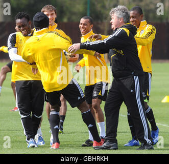 Chelsea Coach Gus Hiddink (zweite rechts) beteiligt sich an Versuchen, Didier Drogba (zurück zur Kamera) die Ohren zu schnallen, ein verspielter Verlust, weil er während einer Trainingseinheit auf dem Cobham Training Ground, Surrey, in einer Kick-about-Sequenz die Kontrolle verlor. Stockfoto