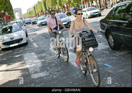 Ein Mann und eine Frau fahren ihre Velib' Fahrräder runter die Champs-Elysees in Paris, Frankreich, 15. Juli 2007. Stockfoto