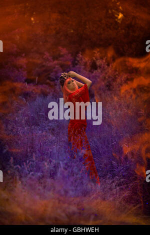 Blonde romantische Fee Elfe Modell in Wiese mit mit lila rose Goldkrone Kopfschmuck, kontemplativen, abstrakt Stockfoto