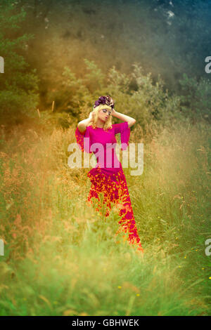 Blonde romantische Fee Elfe Modell in Wiese mit mit gold lila rose Krone Kopfschmuck, kontemplativen, lila Rauch Stockfoto