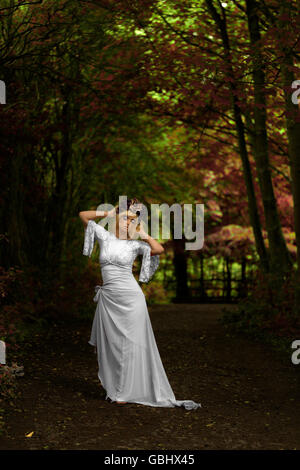 Blonde Braut Porträt, barfuß mit gold lila rose Krone Kopfschmuck, kontemplative im herbstlichen Wald Stockfoto