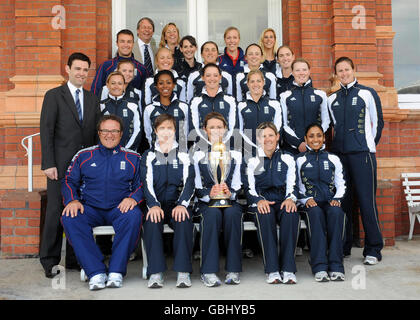 Die Cricket-Captain Charlotte Edwards der englischen Frauen hält die Trophäe, als sie nach einer Pressekonferenz auf dem Lord's Cricket Ground, London, von dem Team begleitet wird. Stockfoto