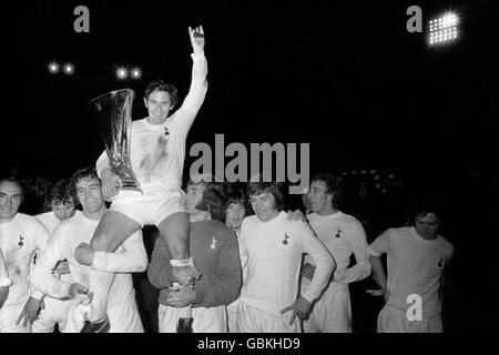 Alan Mullery, Kapitän von Tottenham Hotspur, hält sich am UEFA-Cup fest, als er von seinen jubelten Teamkollegen geleitet wird: (l-r) Alan Gilzean, Martin Peters, Mike England, Mullery, Pat Jennings, Joe Kinnear, Cyril Knowles, Martin Chivers, Steve Perryman Stockfoto