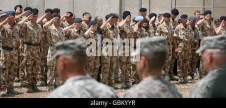 Britische Soldaten grüßen an der Gedenkmauer vor dem Hauptquartier der 20. Panzerbrigade auf der Hauptkoalition-Militärbasis in Basra während eines Dienstes zu Ehren der 179 britischen Soldaten, die während des sechsjährigen Konflikts im Irak getötet wurden. Stockfoto