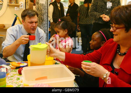 Der Staatssekretär für Kinder, Schulen und Familien, Ed Balls, und die Schulministerin Sarah McCarty Fry, frühstücken mit Takara Garnet (2. Rechts), 10, und Adeola Bootle (Mitte-links), 3, aus dem Little Starz Children's Center in West Norwood, Süd-London. Stockfoto