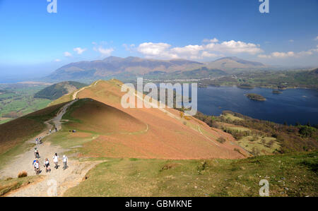 Wanderer folgen dem Pfad zum Gipfel des Cat Bells Fell und blicken über Derwent Water in Richtung Keswick im Lake District. Stockfoto