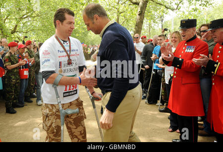 Major Phil Packer, 36, links, der bei einem Angriff in Basra im vergangenen Februar die Beinverwendung verloren hat, wird von Sir Steve Redgrave mit seiner Medaille ausgezeichnet, als er zwei Wochen nach seinem Start in der Mall, London, ankommt, um den Flora London Marathon zu absolvieren. Stockfoto