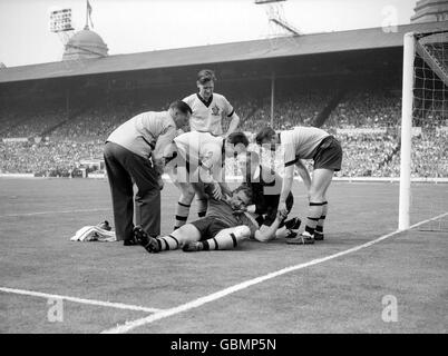 Schiedsrichter Kevin Howley (zweite R) unterstützt den Torhüter von Wolverhampton Wanderers, Malcolm Finlayson (c), während die Teamkollegen George Showell (r), Gerry Harris (zweite L) und Bill Slater (zweite L) seinen Zustand überprüfen Stockfoto