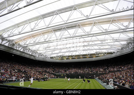 Der britische Tim Henman (links), der zusammen mit seinem Partner Kim Clijsters gegen Andre Agassi und Frau Steffi Graf auf dem Mittelfeld im Rahmen der Centre Court Celebration im All England Lawn Tennis and Croquet Club, Wimbledon, London, Dienst. Stockfoto