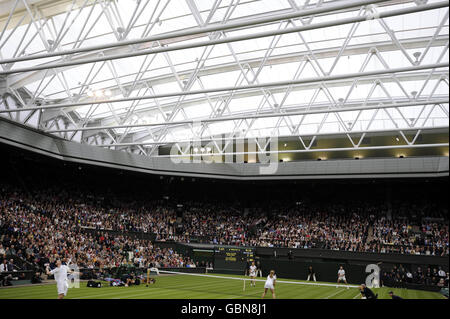 Der britische Tim Henman (links), der zusammen mit seinem Partner Kim Clijsters gegen Andre Agassi und Frau Steffi Graf auf dem Mittelfeld im Rahmen der Centre Court Celebration im All England Lawn Tennis and Croquet Club, Wimbledon, London, Dienst. Stockfoto