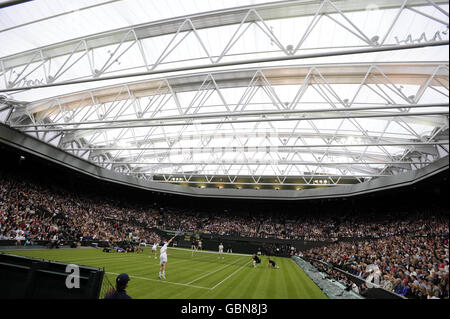 Der britische Tim Henman (Mitte), der zusammen mit seinem Partner Kim Clijsters gegen Andre Agassi und Frau Steffi Graf während der Centre Court-Messe im All England Lawn Tennis and Croquet Club, Wimbledon, London, auf dem Mittelfeld steht. Stockfoto