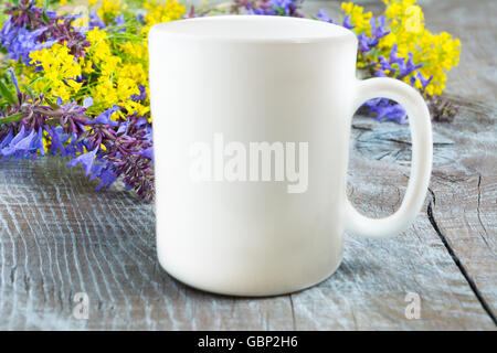 Milchkaffee Tasse Mockup mit lila und gelben Blüten. Leere Becher Mockup mit Platz für Gestaltung oder Text. Milchkaffee Tasse Mock-up. Stockfoto