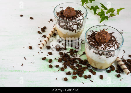 Schlagsahne mit Schokolade Kaffee Cocktail in Gläser auf hellgrünem Hintergrund. Kaffee cremige Dessert mit Kakao. Stockfoto
