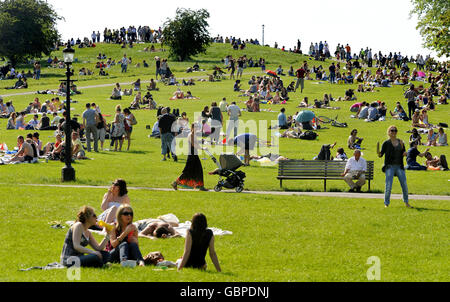 Die Menschen genießen das warme Wetter auf Londons Primrose Hill. Dieses Gebiet war einst Teil einer großen Jagdjagd, die König Heinrich VIII. Angeeignet hatte Im Jahre 1842 wurde es in einen öffentlichen Park umgewandelt. Die Gegend um den Primrose Hill Park ist sehr beliebt bei Prominenten, die aufgrund ihrer böhmischen Atmosphäre in der Gegend leben. Stockfoto