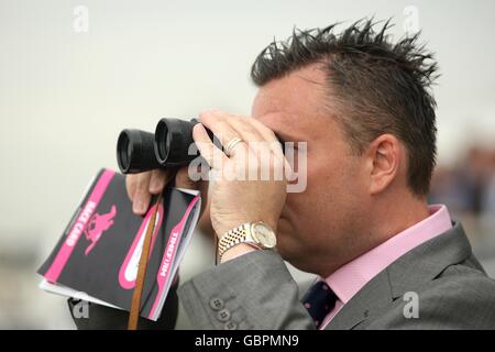 Pferderennen - Investec Derby Festival - Ladies Day - Epsom Racecourse. Ein Rennfahrer blickt durch ein Fernglas auf die Strecke Stockfoto