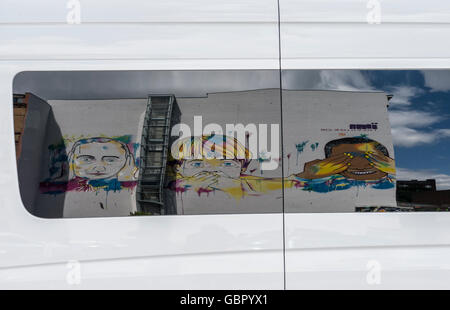 Berlin, Deutschland. 7. Juli 2016. Graffiti mit Bildern von Putin, Merkel und Obama an der Wand des Dorfes IMA Design spiegelt sich im Fenster eines Lieferwagens in der Nähe von Kreuzberg in Berlin, Deutschland, 7. Juli 2016. Foto: PAUL ZINKEN/Dpa/Alamy Live News Stockfoto