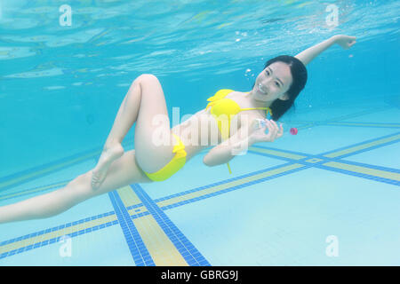 Junge Frau, die im Wasser schwimmen Stockfoto