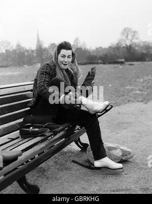 Eine junge Frau zieht ihre Schlittschuhe an, um auf dem Round Pond in Kensington Gardens zu skaten. Stockfoto