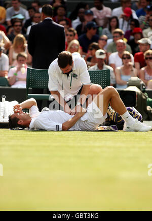 Der Franzose Michael Llodra wird wegen einer Verletzung behandelt, nachdem er während seines Spiels gegen den deutschen Tommy Haas bei den Wimbledon Championships 2009 beim All England Lawn Tennis and Croquet Club, Wimbledon, London, mit einem Ballmädchen zusammengestoßen ist. Stockfoto