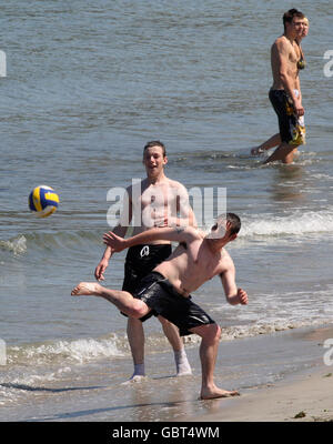 Menschen genießen das heiße Wetter am Strand von Ballygally Co Antrim. Stockfoto