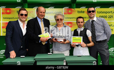 Shane Filan aus Westlife (links) überreicht die Trophäe den siegreichen Verbindungen von Brassini, die von Alan Munroe (2. Von rechts) in den toteswinger Handicap Stakes gefahren werden. Stockfoto