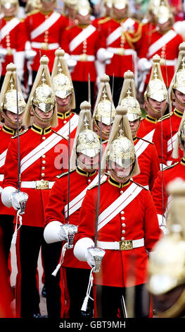 Soldaten marschieren durch das Gelände von Windsor Castle, während Mitglieder der königlichen Familie in der Prozession des Strumpfordens in Windsor spazieren. Stockfoto