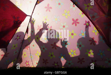 Silhouetten von Festivalbesuchern in einem Campingbereich am Tag vor dem Glastonbury Festival auf der Worthy Farm in Somerset. Stockfoto