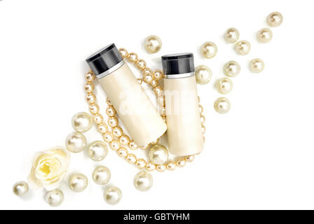 Zwei leere Kosmetikflaschen auf Perlen auf einem Tisch liegend. Studio auf weißem Hintergrund gedreht. Stockfoto