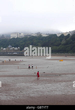 Eine ruhige Szene am Strand von South Bay in Scarborough, während die Wolke von der Nordsee über Oliver's Mount hängt. Stockfoto