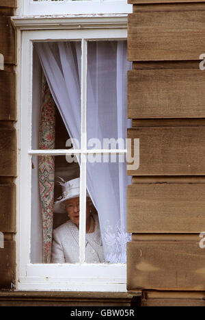 Ihre Majestät die Königin, Oberst-in-Chief schaut aus einem Fenster, während die Offiziere sich für ein Foto mit der Königin während eines Besuchs der Royal Scots Dragoon Guards in Redford Barracks, Edinburgh Stockfoto