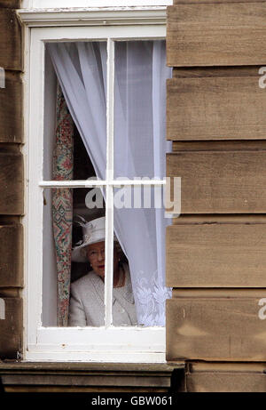 Ihre Majestät die Königin, Oberst-in-Chief schaut aus einem Fenster, während die Offiziere sich für ein Foto mit der Königin während eines Besuchs der Royal Scots Dragoon Guards in Redford Barracks, Edinburgh Stockfoto