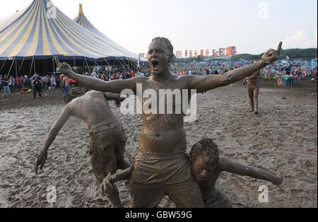 Festivalbesucher, die nach einem Wrestling-Match während des Glastonbury Festivals 2009 auf der Worthy Farm in Pilton, Somerset, in Schlamm gehüllt waren. Stockfoto