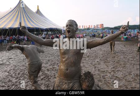 Festivalbesucher, die nach einem Wrestling-Match während des Glastonbury Festivals 2009 auf der Worthy Farm in Pilton, Somerset, in Schlamm gehüllt waren. Stockfoto