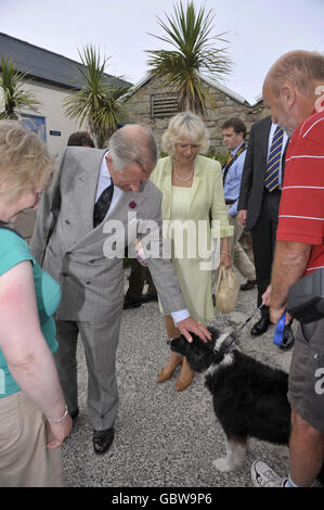 Der Prinz von Wales und die Herzogin von Cornwall treffen Tess, den Collie-Hund, mit Besitzer Pete Flower, als sie nach ihrem Besuch im Gig Boat Club in Porthmellon, St Mary's, Isles of Scilly aufbrechen. Stockfoto