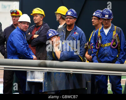 Arbeiter auf einer Werft in Govan, Glasgow, sehen während des symbolischen „Schneidens von Stahl“ des Rumpfes des ersten der beiden neuen Flugzeugträger Großbritanniens zu. Stockfoto