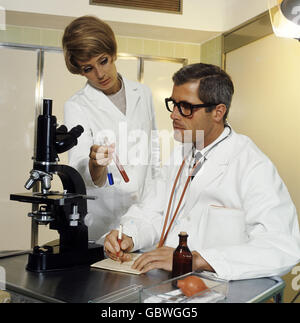 Medizin, Mediziner, Sanitäter mit Assistenz, die mit Mikroskop arbeiten, 1960er, , zusätzliche-Rechte-Clearenzen-nicht verfügbar Stockfoto