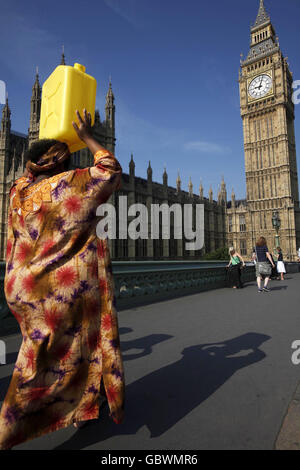 Eine Afrikanerin in traditioneller Kleidung trägt eine mit Wasser gefüllte jerry-Dose von der Themse zur Downing Street in London, wo sie - zusammen mit anderen afrikanischen und asiatischen Frauen - 80,000 Briefe der britischen Öffentlichkeit im Namen der Kampagne „Ende der Wasserarmut“ übergeben wird. Stockfoto