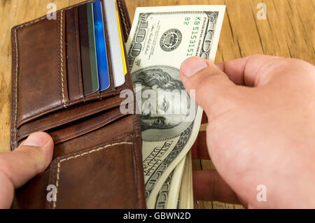 Männliche Hand nehmend Dollar aus einem Leder-Portemonnaie Stockfoto