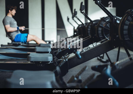 Mann im Fitnessraum am Rudergerät. Stockfoto