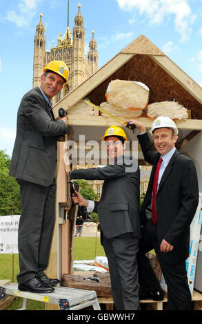 Grand Designs-Moderator Kevin McCloud (links) mit dem Minister für Energie und Klimawandel Ed Miliband (Mitte) und dem Wohnungsminister John Healey, der sich am Bau einer isolierten Konstruktion in Victoria Tower Gardens, Westminster, London, beteiligt, um die Grand Designs Great British Refurb Campaign zu starten, Die Regierung wird aufgefordert, eine landesweite grüne Sanierung von Häusern zu starten, um Energie zu sparen und die CO2-Emissionen zu reduzieren. Stockfoto